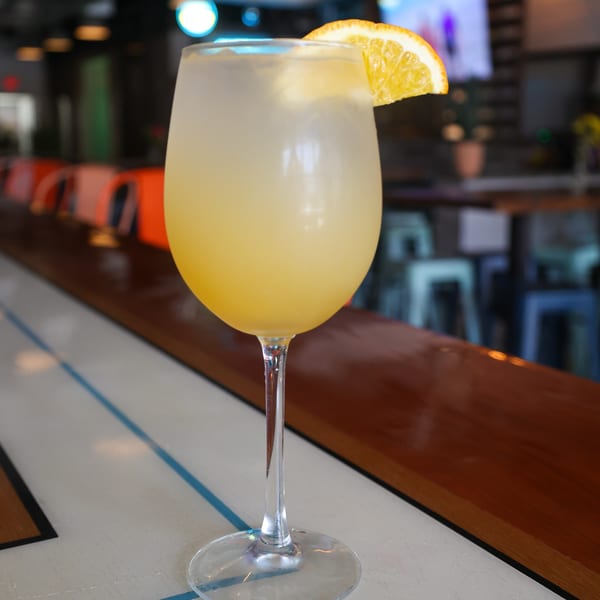 A Spycoast Kitchen & Cocktails mimosa with an orange slice garnish sits on a bar.